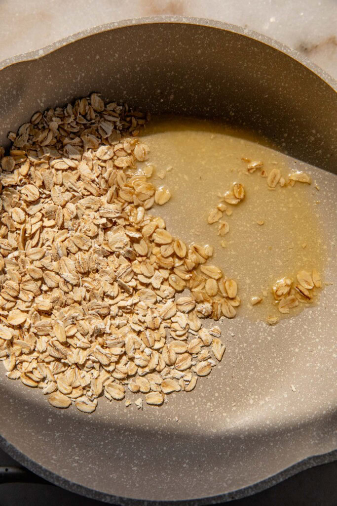 Toasting the oats in a pan with butter.
