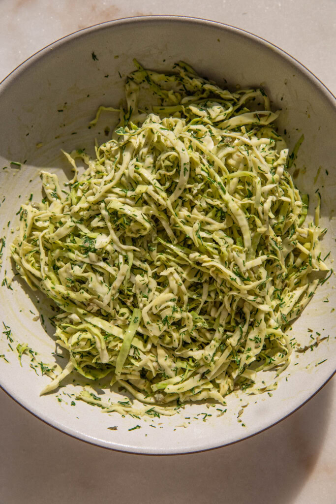 Mixed lemon dill slaw in a mixing bowl.