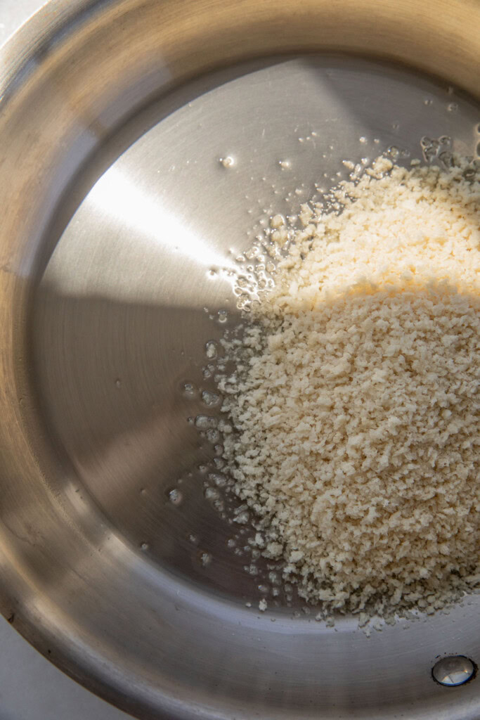 Adding the panko into a pan with oil.