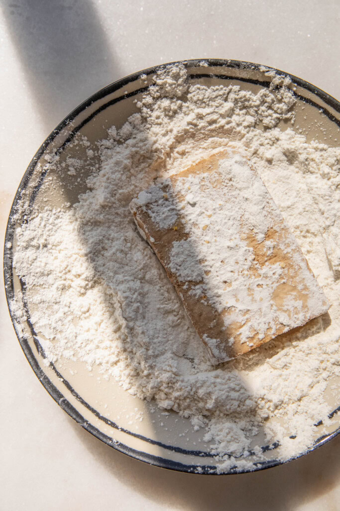 Coating the tofu in cornstarch.