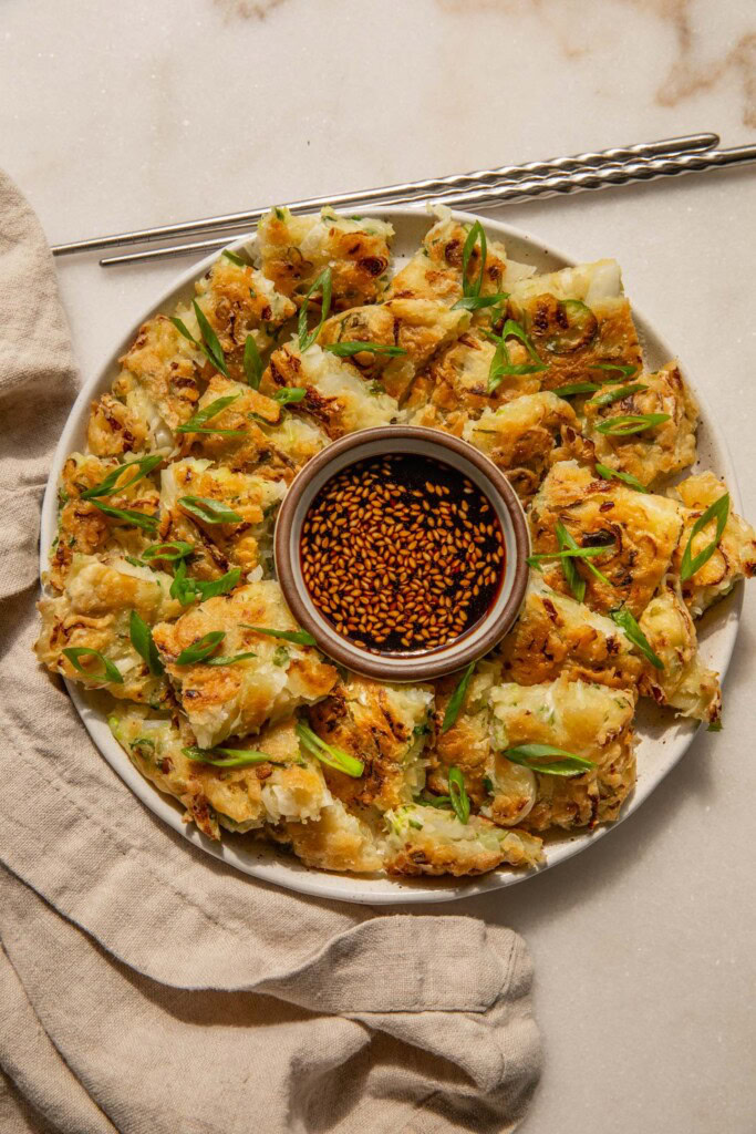 Sliced veggie pancakes arranged around a dish filled with dip in the center.