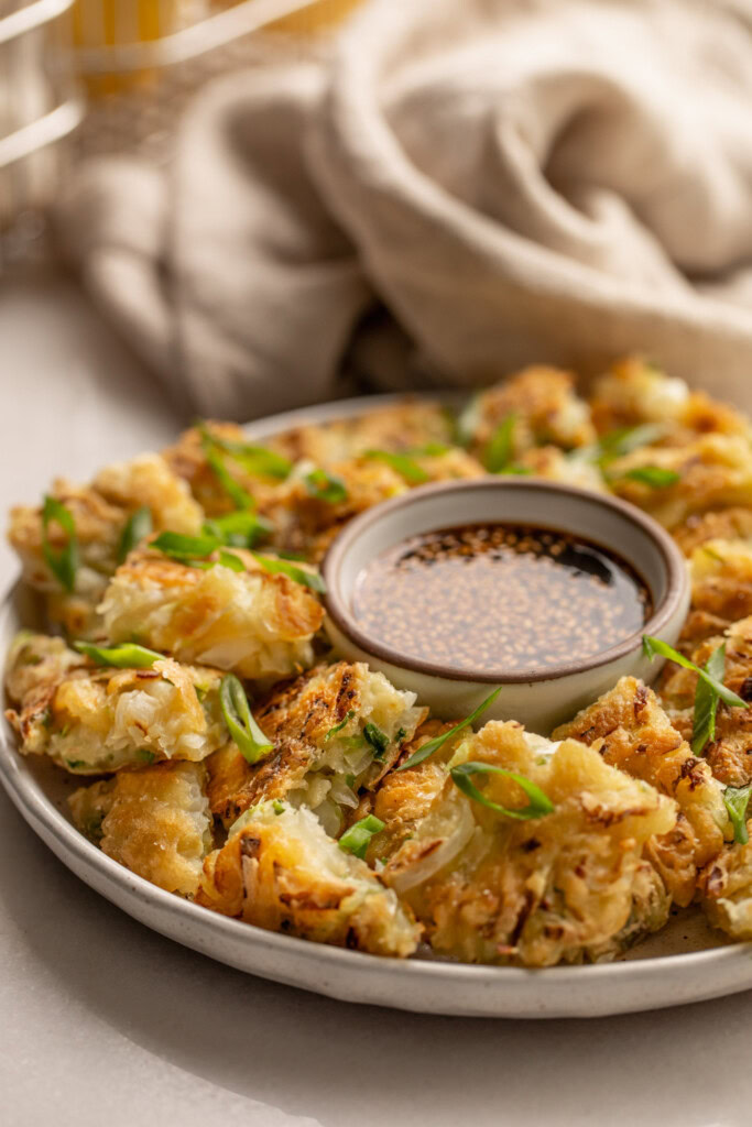Plate of veggie pancakes served with a bowl of dip.