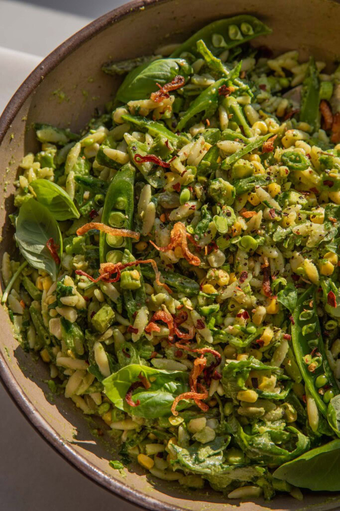 Mixing bowl filled with pasta salad tossed with basil vinaigrette.