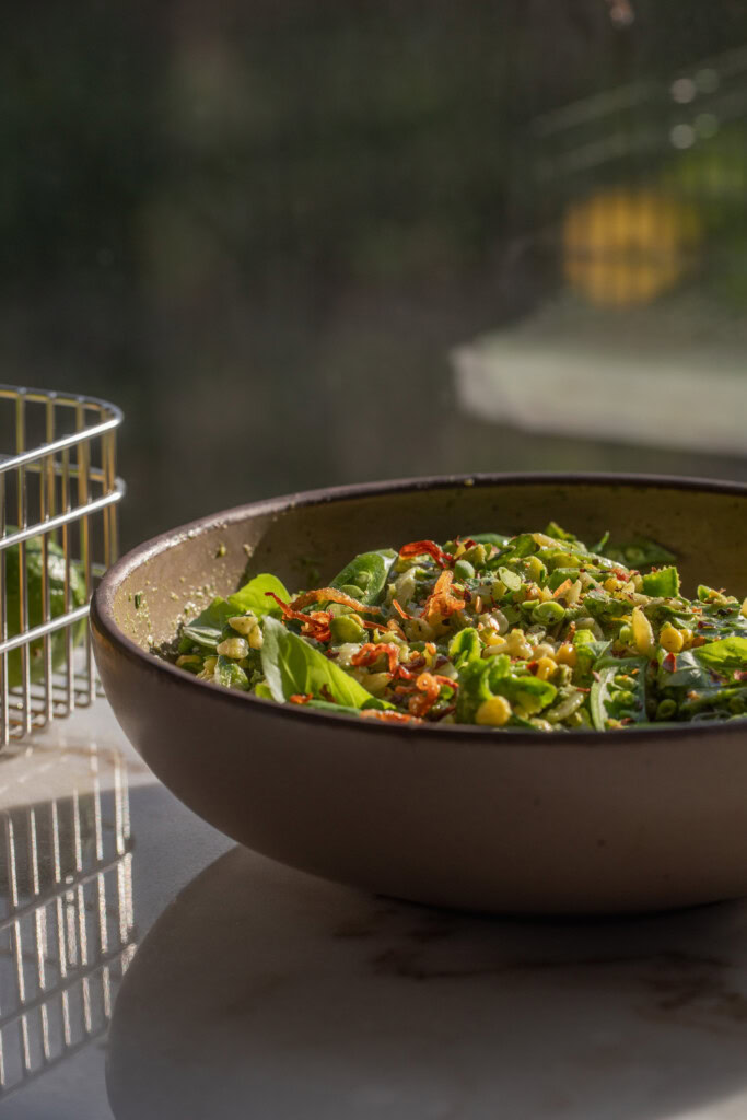 Bowl of orzo pasta salad tossed in a basil vinaigrette.