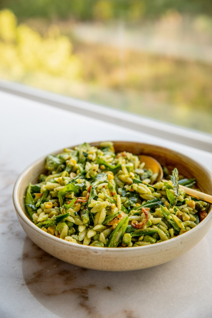 A serving of pasta salad being enjoyed with a gold spoon.