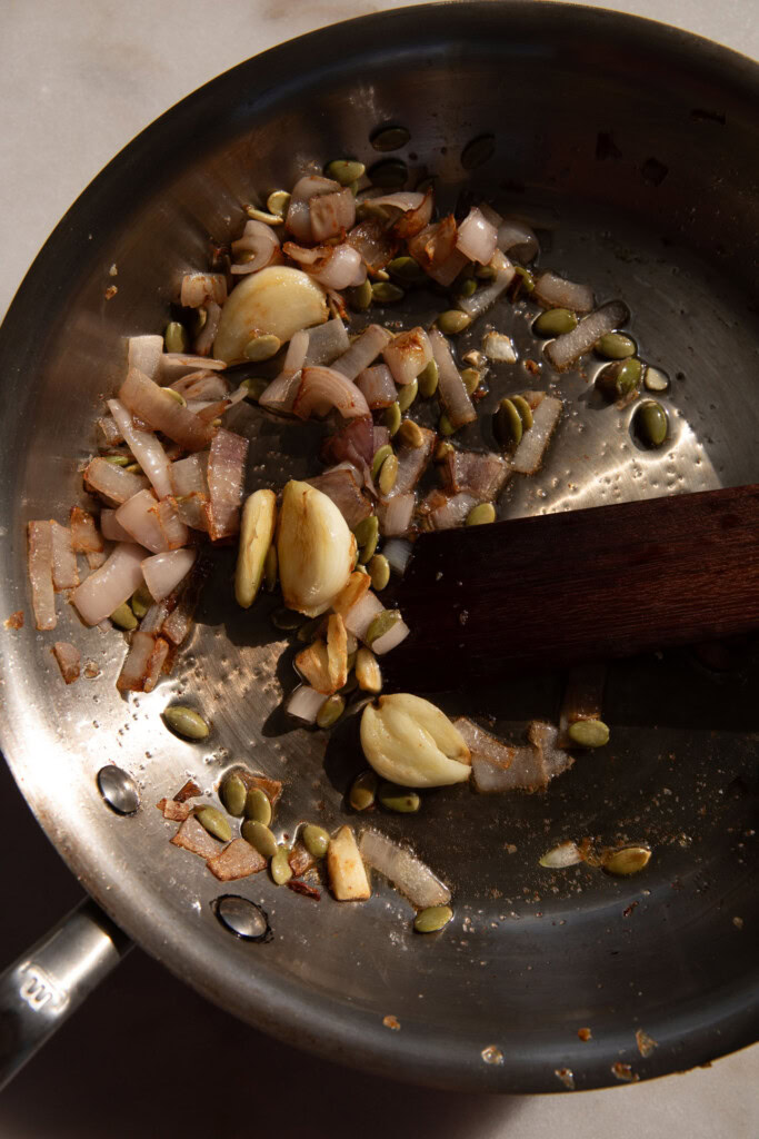 Adding the pepitas to the cooked onions and garlic.