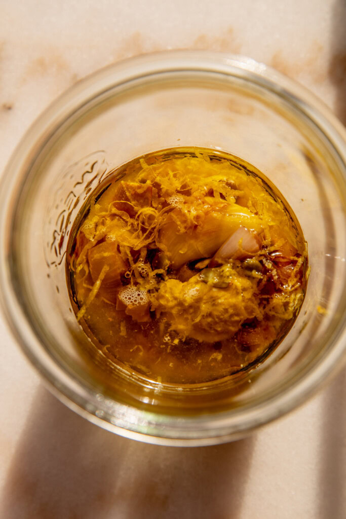 Jar with oil, onion, garlic, mustard, lemon and vinegar.
