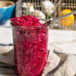 View of a fork pulling the marinated red cabbage slaw from the top of the jar.