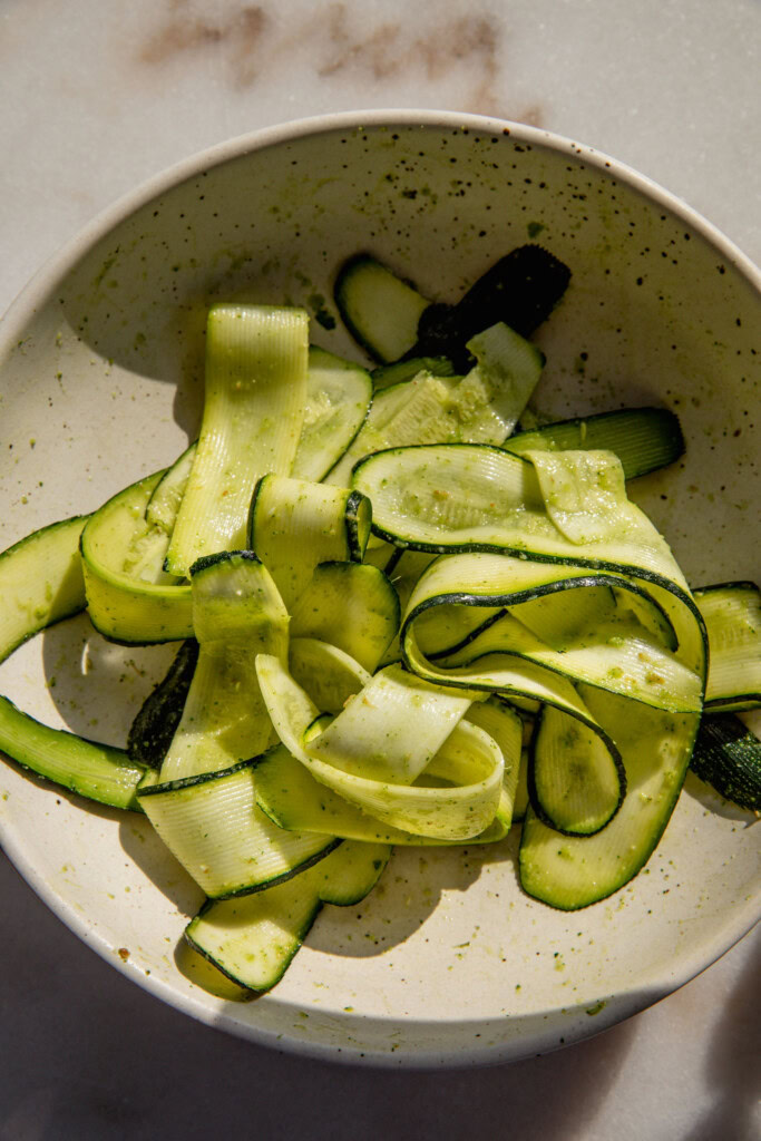 Marinated zucchini ribbons in a bowl.