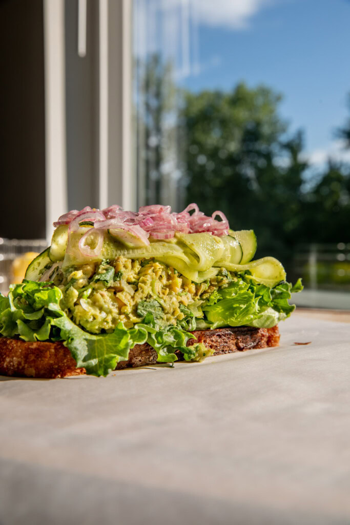 Sandwich stacked high with lettuce, chickpea salad, marinated zucchini, and pickled onions.