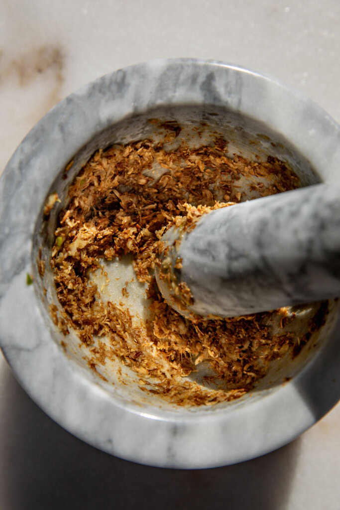 Ground cumin seeds, coriander seeds and garlic in a mortar and pestle.