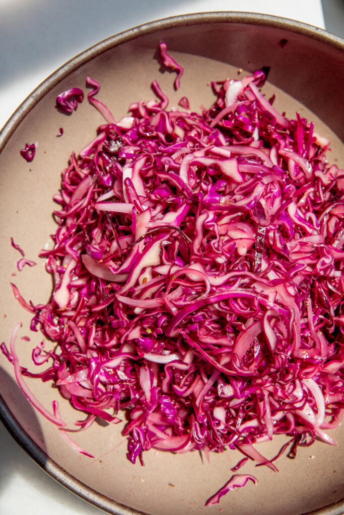 Pink slaw mixed together in a mixing bowl.