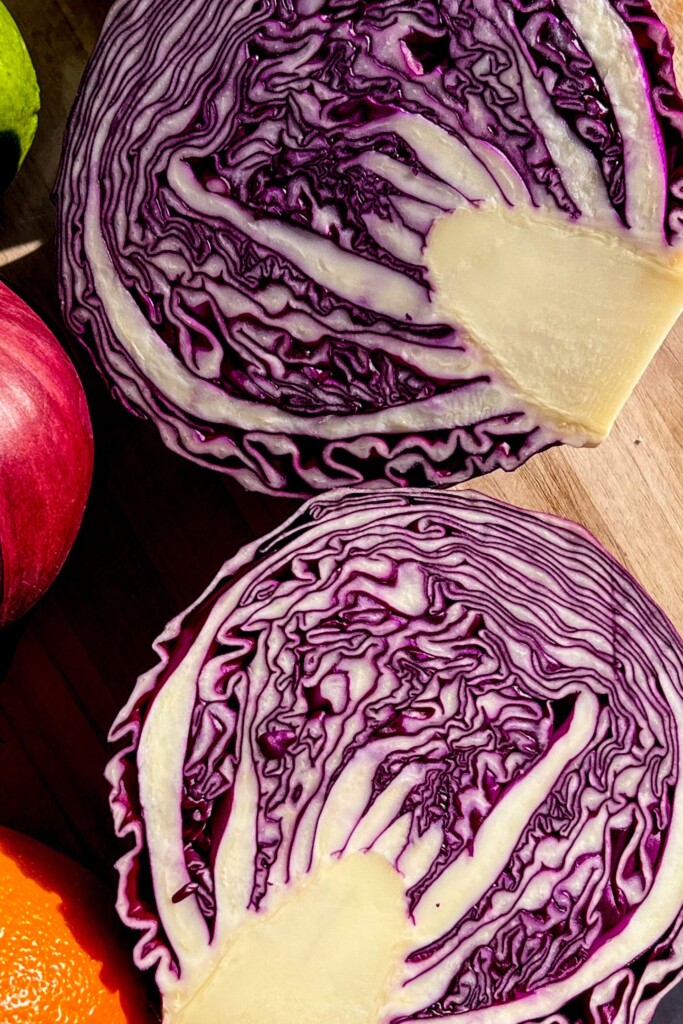 Red cabbage cut in half on a cutting board.