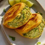 Close up of two arepas on a plate stuffed with tofu salad and guasacaca.