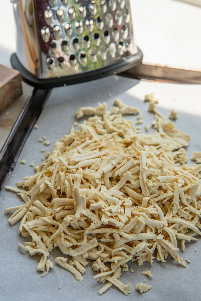 The tofu fully shredded using a box grater on a lined baking tray.