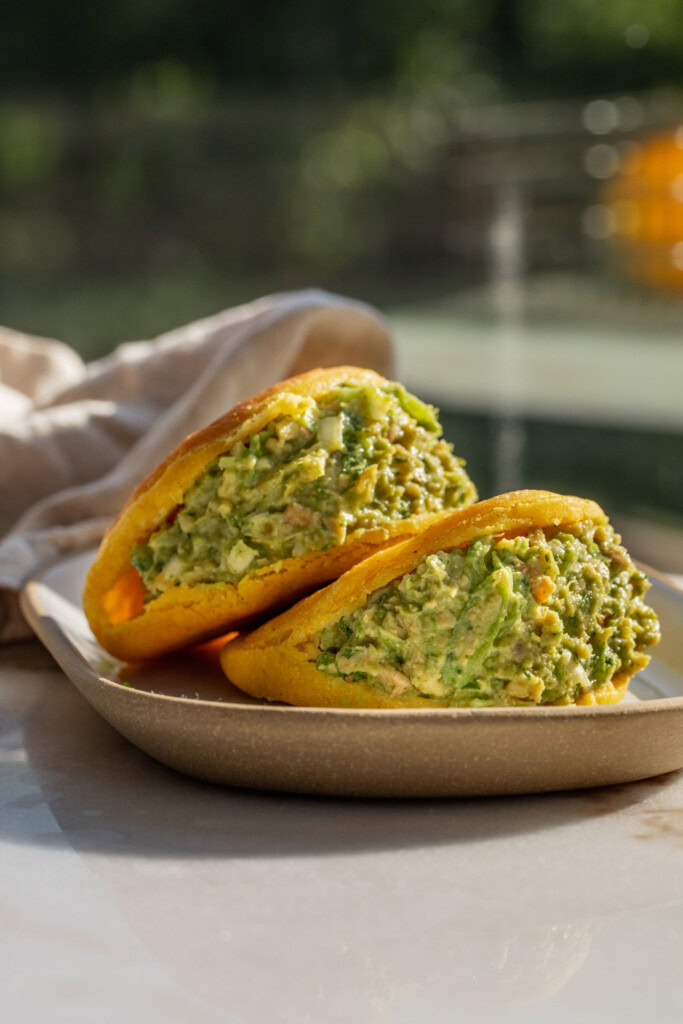 Side view of a tofu salad stuffed into two arepas.