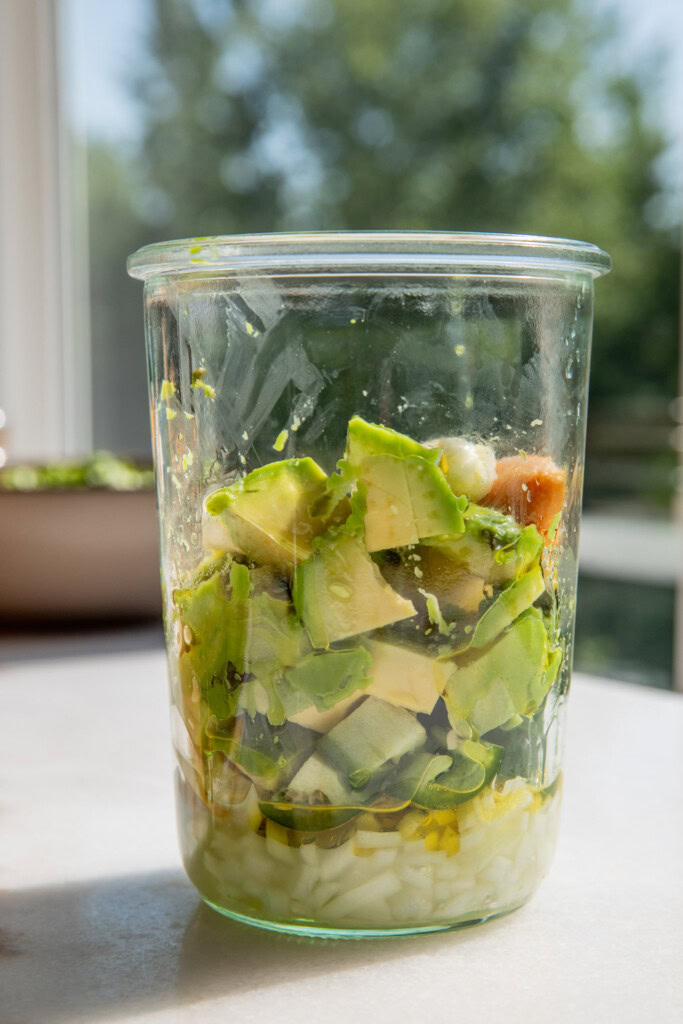 Avocado, garlic, paste, vinegar, lime, and oil in a blender cup.