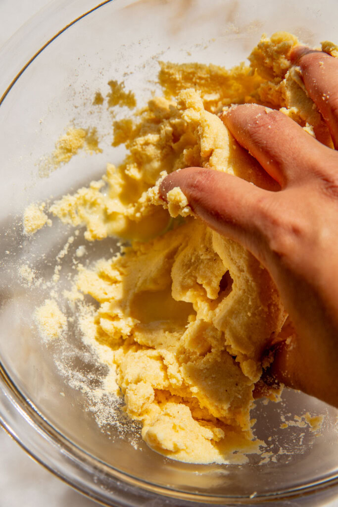 Mixing the water with the cornmeal to make a dough in a bowl.