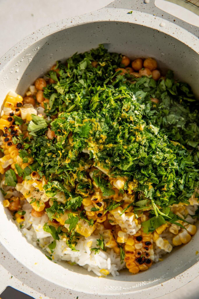 Rice pot filled with chickpeas, corn, herbs, and lemon.