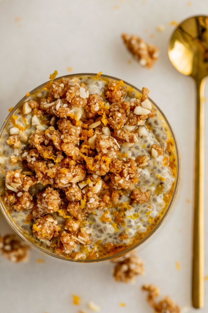 Jar of chia pudding and crumble on top with a gold spoon set to the side of the jar.