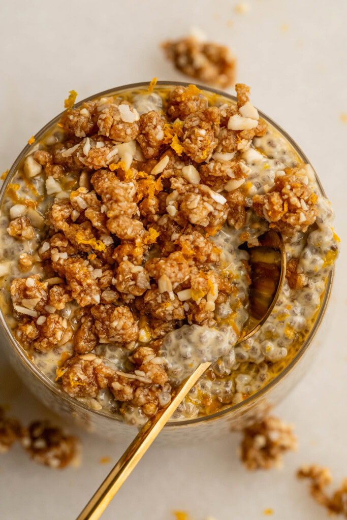 Close up of a spoon digging into the top of a jar of chia pudding and crumble.