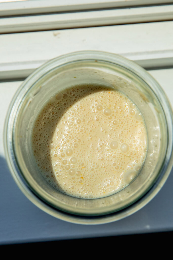 Blended orange juice, yogurt, and evaporated milk in a blender cup.
