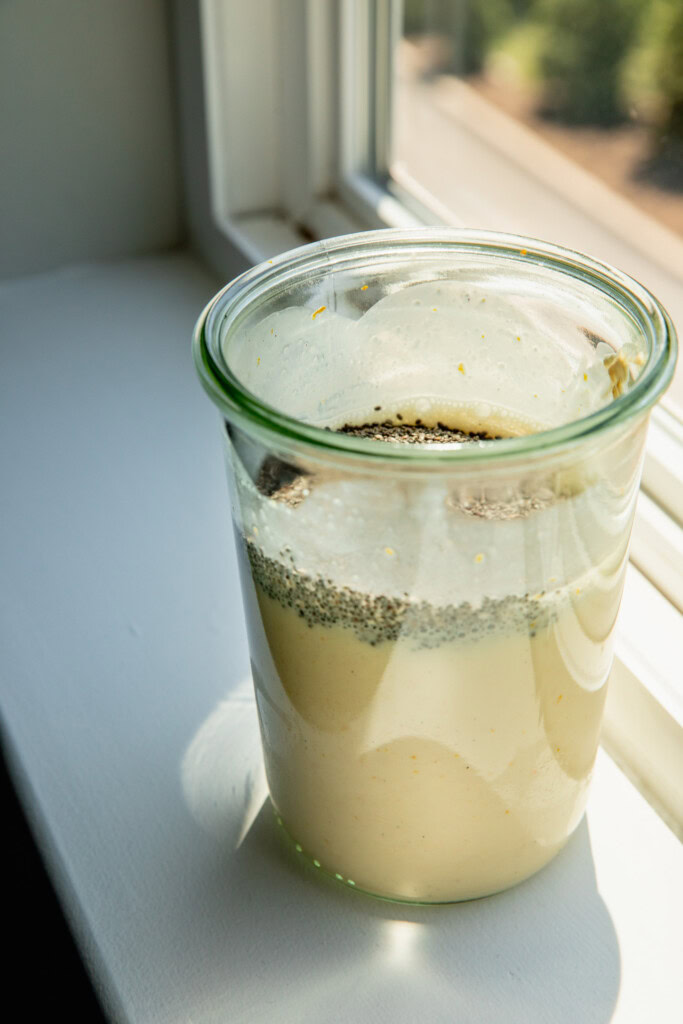 Chia seeds added to container of blended orange milk.