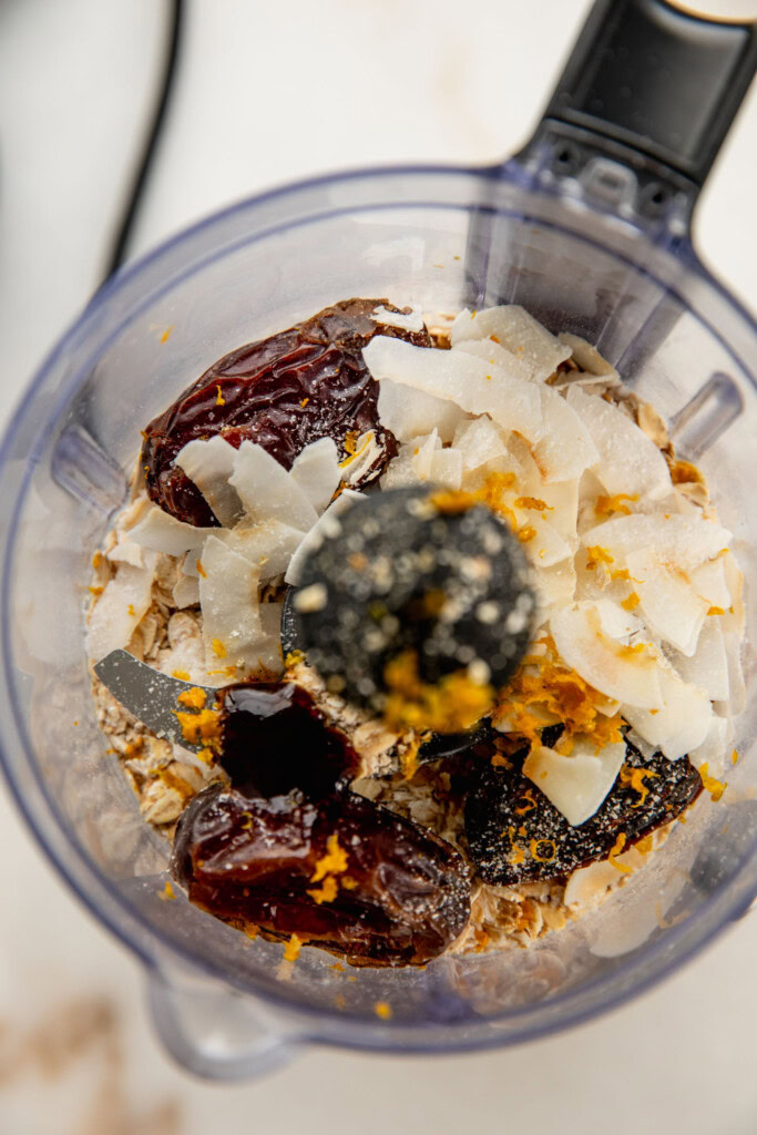 Food processor with oats, dates, coconut flakes, and orange zest.