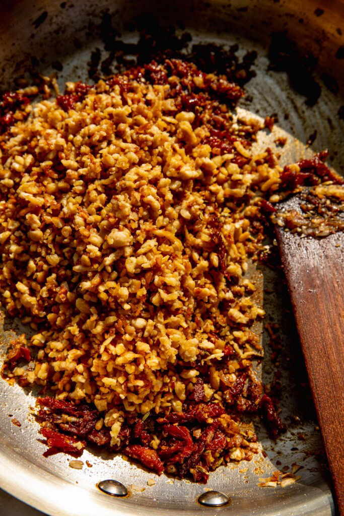 Stirring the tempeh together with the spiced tomato mixture.
