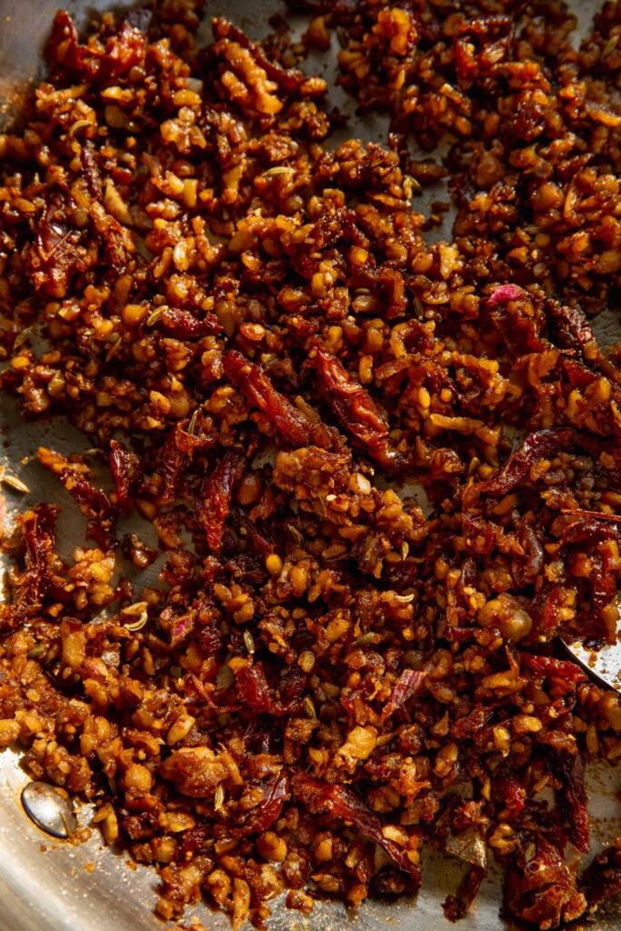 Fully cooked spiced tempeh and sun-dried tomatoes in a pan.