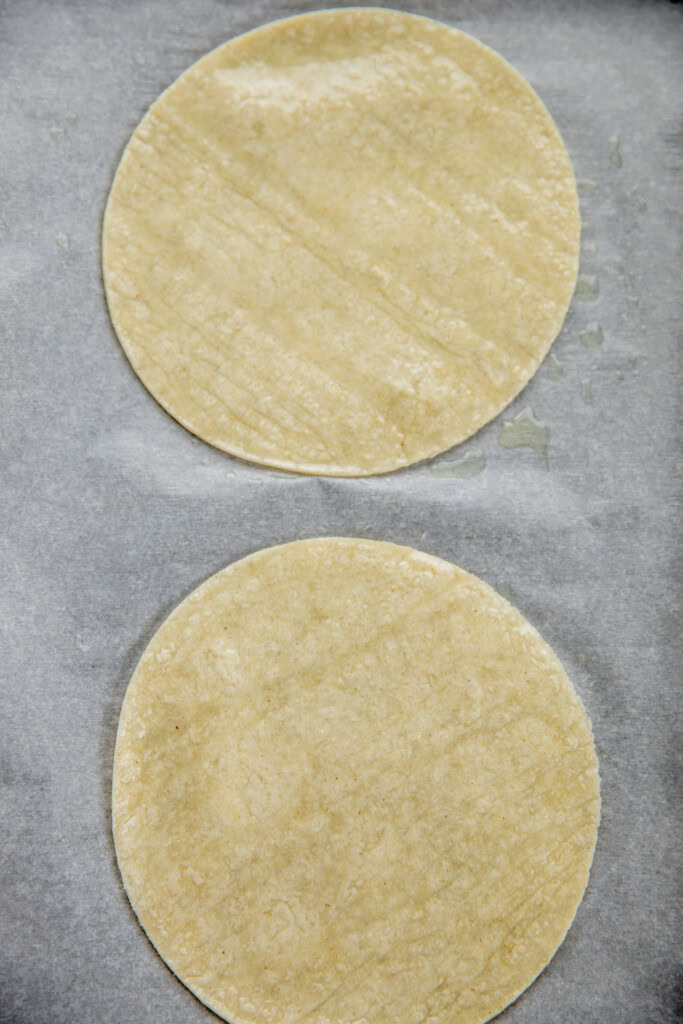 Tortillas sprayed with oil on a baking tray.