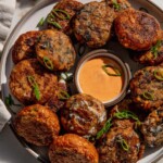 Plate of three different tofu patties situated around a bowl of dipping sauce.