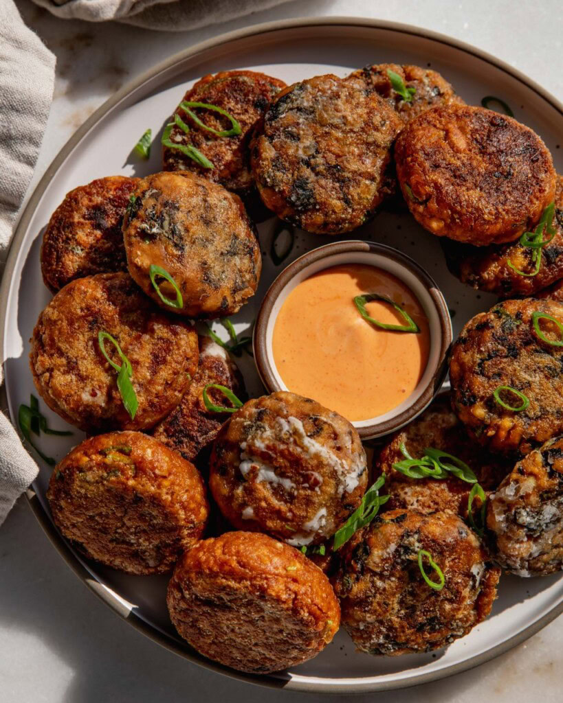 Plate of three different tofu patties situated around a bowl of dipping sauce.