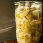 Sunlight hitting a glass container filled with cubed tofu in a feta-style marinade.