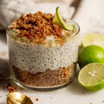 Close up of a jar of chia pudding layered with graham cracker crumb with key limes set on the side.