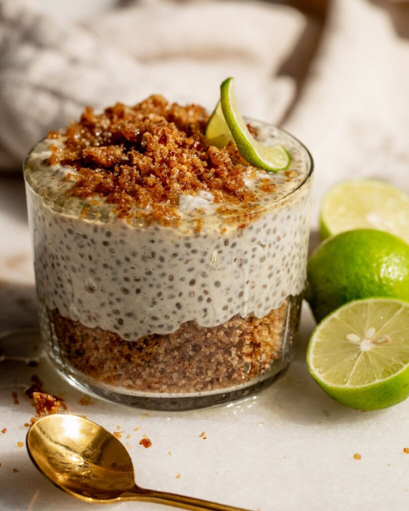 Close up of a jar of chia pudding layered with graham cracker crumb with key limes set on the side.