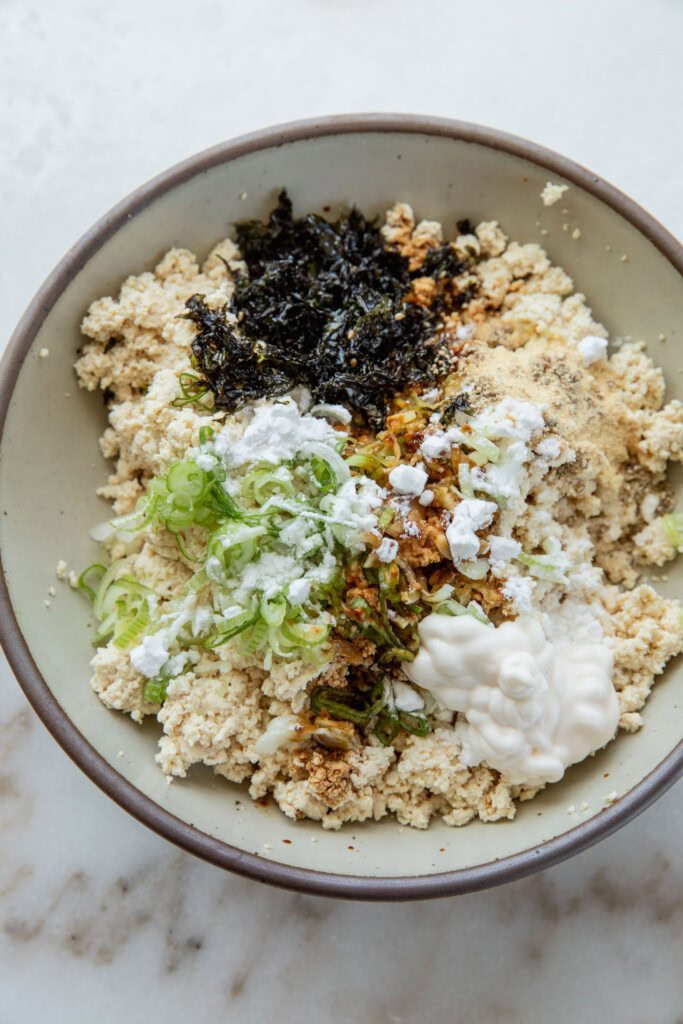 Bowl filled with tofu, scallions, potato starch, seaweed, sesame, and seasonings.