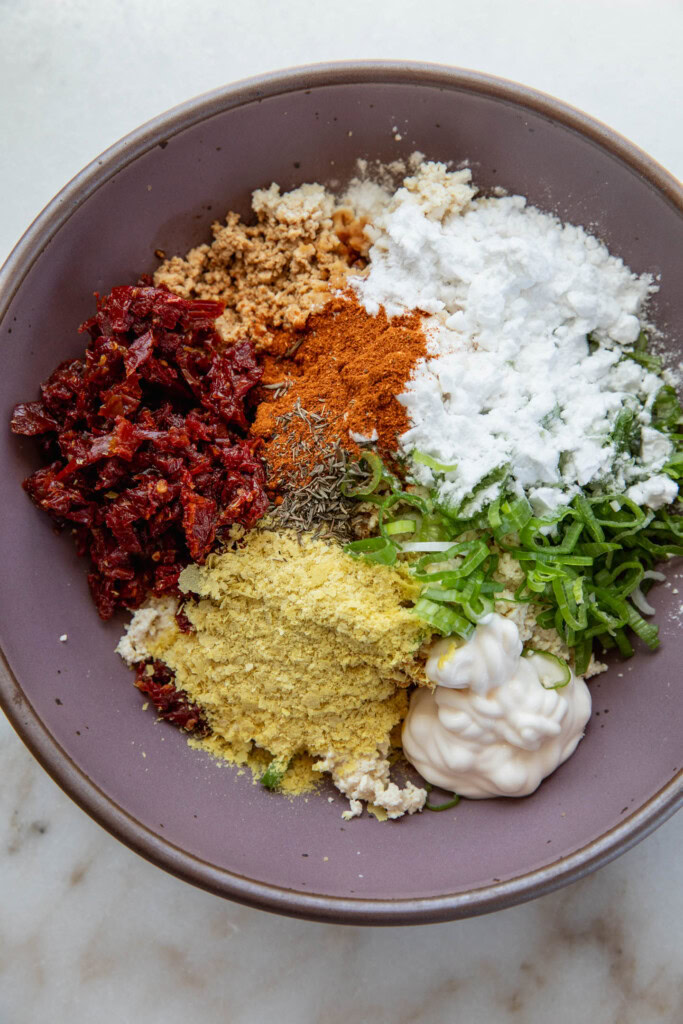 Bowl of tofu, sun-dried tomatoes, nutritional yeast, seasonings, mayo, and soy sauce.