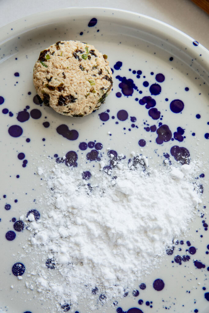 Dusting the patties with a little potato starch on a plate.