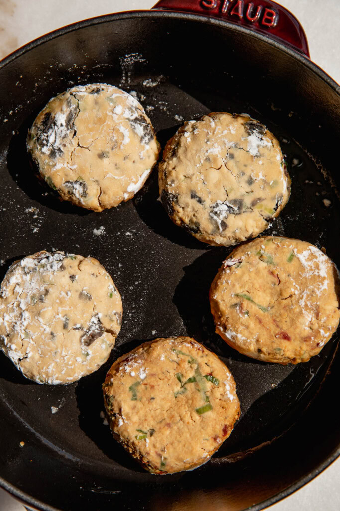 Cooking the dusted tofu patties in a pan.