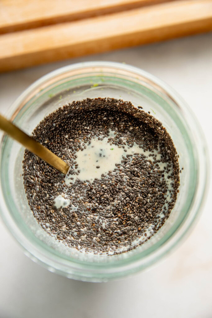 Adding the chia seeds into the blended milk to stir in with a spoon.