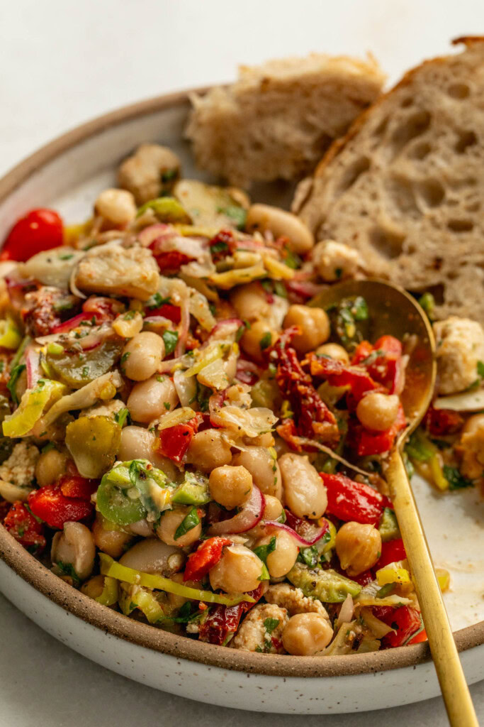 Close up of a plate filled with bean salad being spooned up with bread tucked on the side.