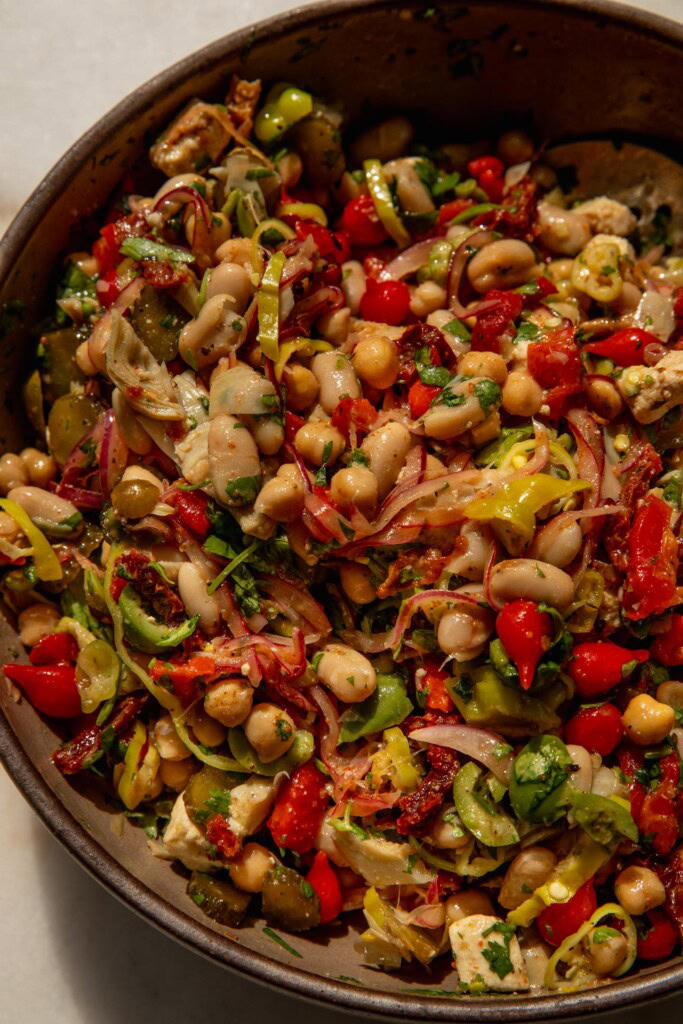 All the jarred pickled veggies tossed together with beans and dressing in a mixing bowl.