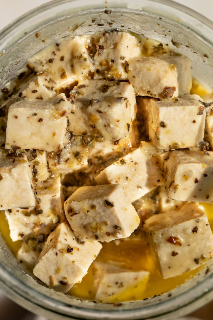 Close up of a jar filled with marinated tofu.