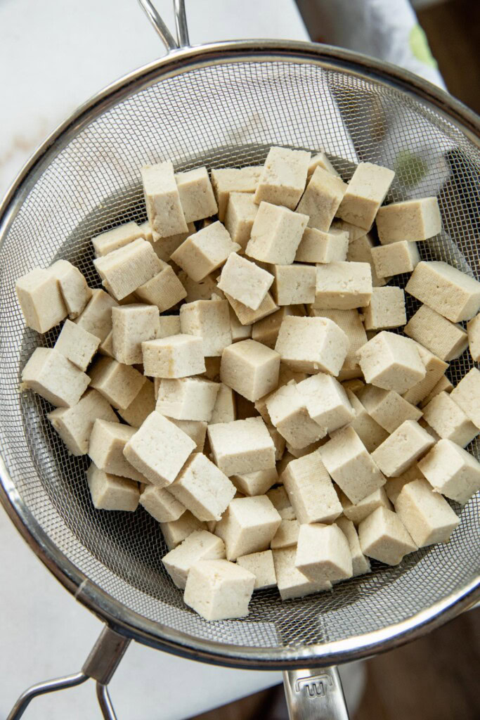 Draining the tofu in a mesh sieve after boiling.
