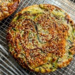 A cooked zucchini pancake laying on top of a cooling rack.