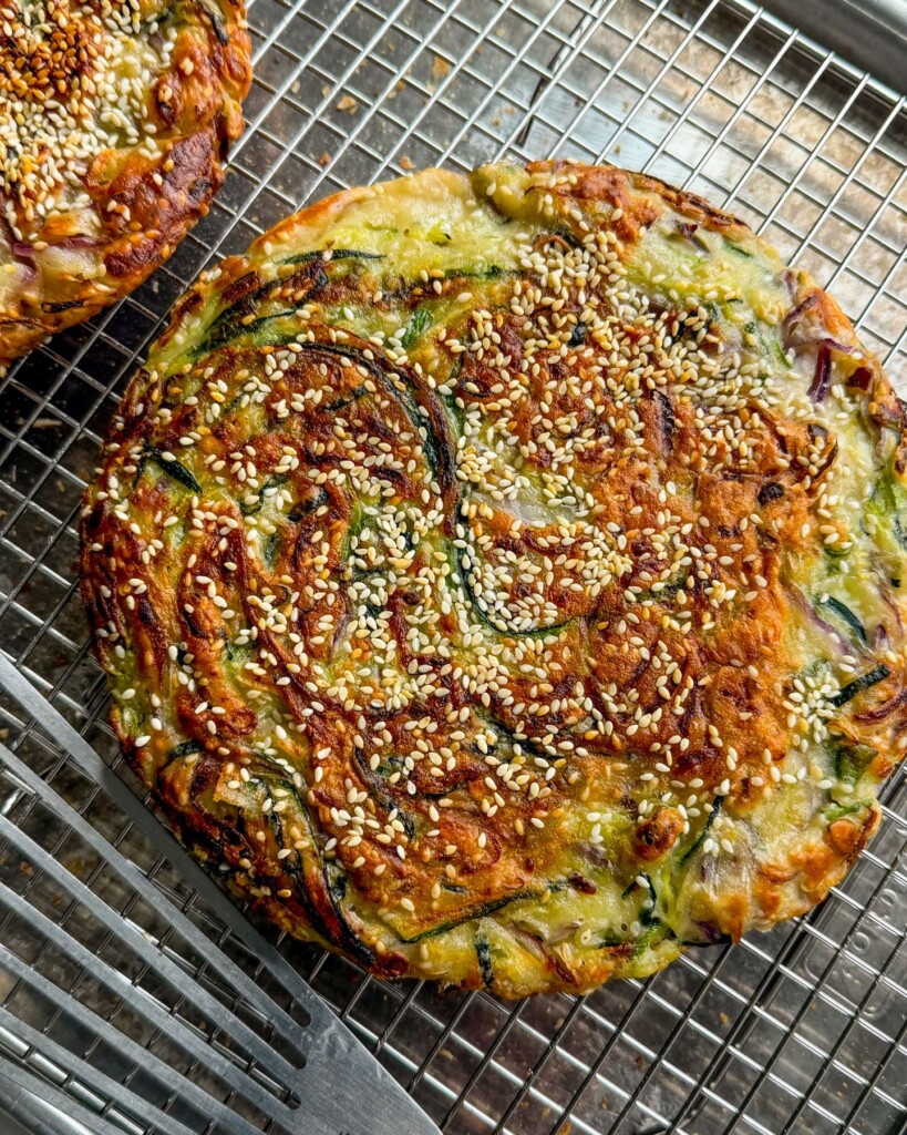 A cooked zucchini pancake laying on top of a cooling rack.