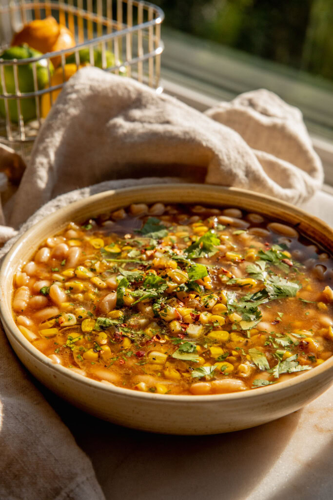 Bowl of beans simmered in corn and ancho chilies topped with crispy corn and cilantro.