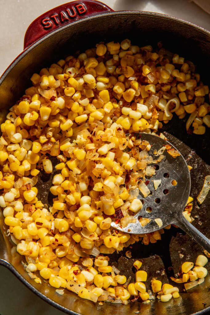 Corn charred in a pan with onions and red pepper flakes.