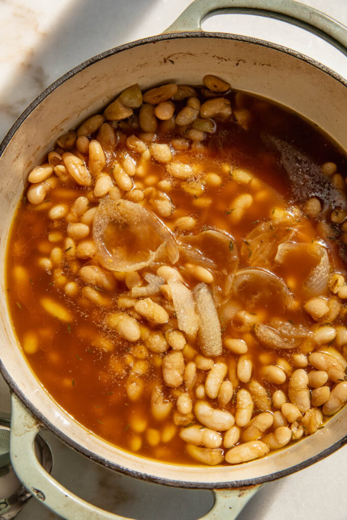 Pot of beans after removing the onion, garlic bulbs, thyme, chilies, corn cobs, and bay leaf.